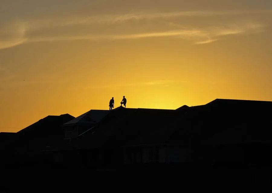 Roofing workers assessing storm damage on a rooftop